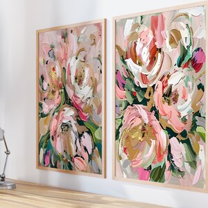 以下が含まれることがあります： ピンク、白、金色のアクセントが施された、抽象的な花の絵画が2つ額装されています。絵画は白い壁に飾られています。