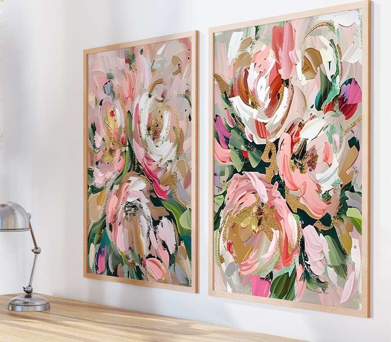 以下が含まれることがあります： ピンク、白、金色のアクセントが施された、抽象的な花の絵画が2つ額装されています。絵画は白い壁に飾られています。