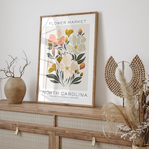 May include: A printable art print featuring a floral design with pink, white, and yellow flowers. The print has the text "FLOWER MARKET" at the top and "NORTH CAROLINA OFFICIAL STATE FLOWER - DOGWOOD" at the bottom.