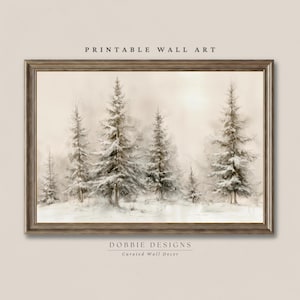 Peut inclure: Une impression d'art mural encadrée horizontale représentant une forêt hivernale avec des conifères enneigés dans des tons beige, crème et brun doux. Le texte PRINTABLE WALL ART figure en haut et DOBBIE DESIGNS Curated Wall Decor en bas.