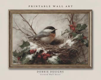 May include: A framed wall art print titled PRINTABLE WALL ART and DOBBIE DESIGNS Curated Wall Decor. The image depicts a black-capped chickadee perched in a nest surrounded by green holly leaves, red berries, and white snow against a muted background.