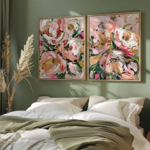以下が含まれることがあります： 緑色の背景にピンク、白、金の花が描かれた、額縁に入った抽象的な花の絵画が2枚。絵画は、白い寝具と緑色の毛布を敷いたベッドの上に飾られています。