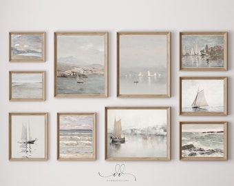 May include: A gallery wall of nine framed watercolor paintings depicting seascapes with sailboats. The paintings are in shades of blue, gray, and white, with hints of pink and brown. The frames are a light wood color.