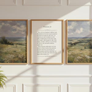May include: Three framed landscape art prints with a pastoral scene in muted tones. The center frame features the text of Psalm 23. The frames are a light wood color, and the artwork depicts a field and sky.