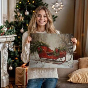 May include: A canvas print featuring a red sleigh decorated with evergreen boughs and red bows, set against a snowy forest backdrop. The artwork evokes a winter holiday theme, perfect for seasonal decor.