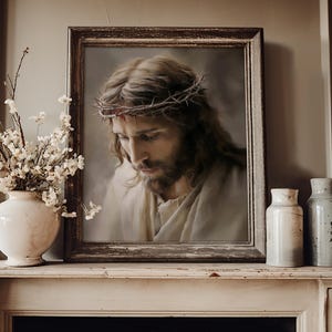 May include: A framed portrait of a man with long brown hair and a beard wearing a crown of thorns. The artwork is displayed on a mantelpiece next to a white vase filled with white flowers and two cylindrical ceramic containers.