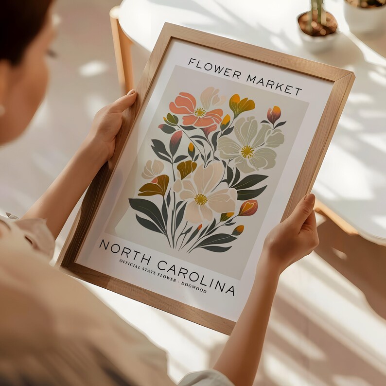 May include: A framed print with a floral design featuring pink, white, and yellow flowers. The print reads "Flower Market" and "North Carolina, Official State Flower - Dogwood".