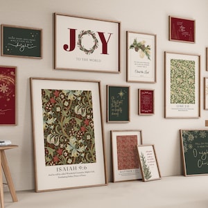 Puede incluir: Una colección de impresiones artísticas enmarcadas con temática navideña. Las impresiones presentan texto, patrones florales e imágenes festivas en varios tamaños y colores, incluyendo rojo, verde y dorado. Los marcos son de color marrón claro.