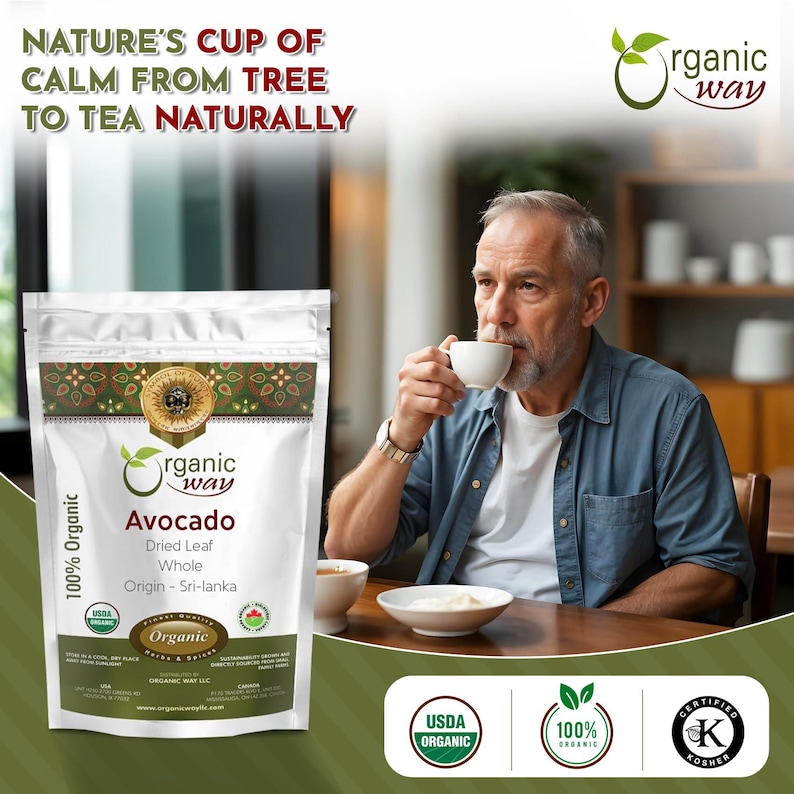 May include: A bag of Organic Way Avocado tea with the text "Nature's Cup of Calm from Tree to Tea Naturally" on the top. The bag is white with green and gold accents. The text "100% Organic" is on the left side of the bag. The bag is sitting on a wooden table. A man is drinking from a white mug. The text "Organic Way" is on the bag. The text "Avocado Dried Leaf Whole Origin - Sri-lanka" is on the bag. The text "USDA Organic" is on a green circle with white text. The text "100% Organic" is on a green circle with white text. The text "Certified Kosher" is on a green circle with white text.