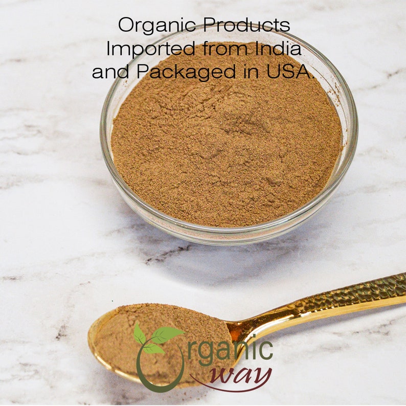 May include: A clear glass bowl filled with a fine, brown powder, likely a spice or herb. A gold spoon holds a portion of the powder, with the text "organic way" and a leaf logo. The image also includes the text "Organic Products Imported from India and Packaged in USA."