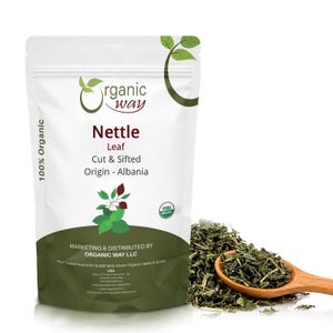 May include: A white stand-up pouch of Organic Way Nettle Leaf, cut and sifted, from Albania. The label features the Organic Way logo, USDA Organic seal, and text. A wooden spoon filled with dried green nettle leaves sits beside the pouch.