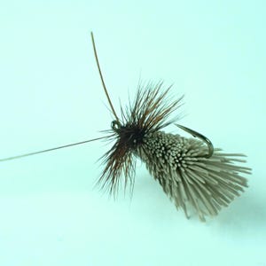 Puede incluir: Una taza de cerámica blanca con un asa negra y el texto "But First, Coffee" en negrita negra. La taza se encuentra sobre un fondo neutro, resaltando su diseño sencillo.