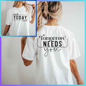 以下が含まれることがあります： 白地に黒文字で「Make Today Great」と書いてあるTシャツ。後ろには「Tomorrow Needs You」と書いてある。
