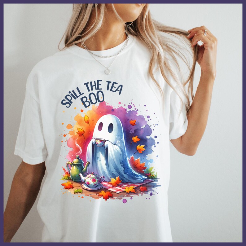 Pu&ograve; includere: Maglietta bianca con un design acquerellato colorato di un fantasma che tiene una tazza di t&egrave;. Il testo "Spill the Tea Boo" &egrave; stampato in nero sopra il fantasma.