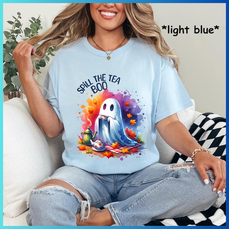 Pu&ograve; includere: Una maglietta blu chiaro con un'immagine di un fantasma che beve il t&egrave; e il testo "Spill the Boo Tea".