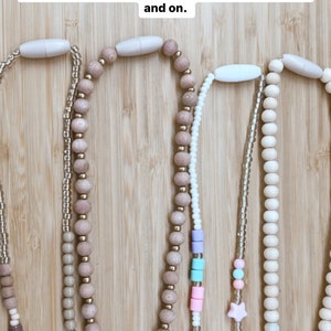 May include: Five wooden bead lanyards with different colored beads and charms. The lanyards are on a wooden surface. All lanyards from Modern Made Company come with a plastic breakaway clasp. These are only to be used for emergency catches or pulls and not to be used to take the lanyard off and on.