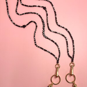 May include: Two black beaded necklaces with gold clasps and tassels. One necklace has the word "FIRST GRADE" spelled out in black beads.