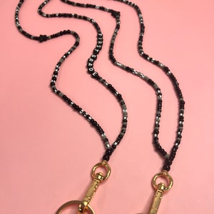 May include: Black and white beaded lanyard with gold clasps and a black beaded charm with the text "FIRST GRADE" in white letters.