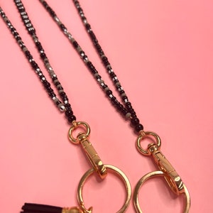 May include: Two black and white beaded lanyards with gold clasps and tassels. The lanyards have a gold charm with the text "FIRST GRADE" on it.