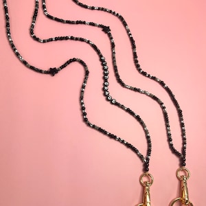 May include: Two black and white beaded lanyards with gold clasps. The lanyards have the word "FIRST GRADE" spelled out in black beads.