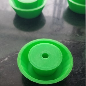 May include: Three bright green plastic circular objects with a hole in the center. The objects are stacked on top of each other.