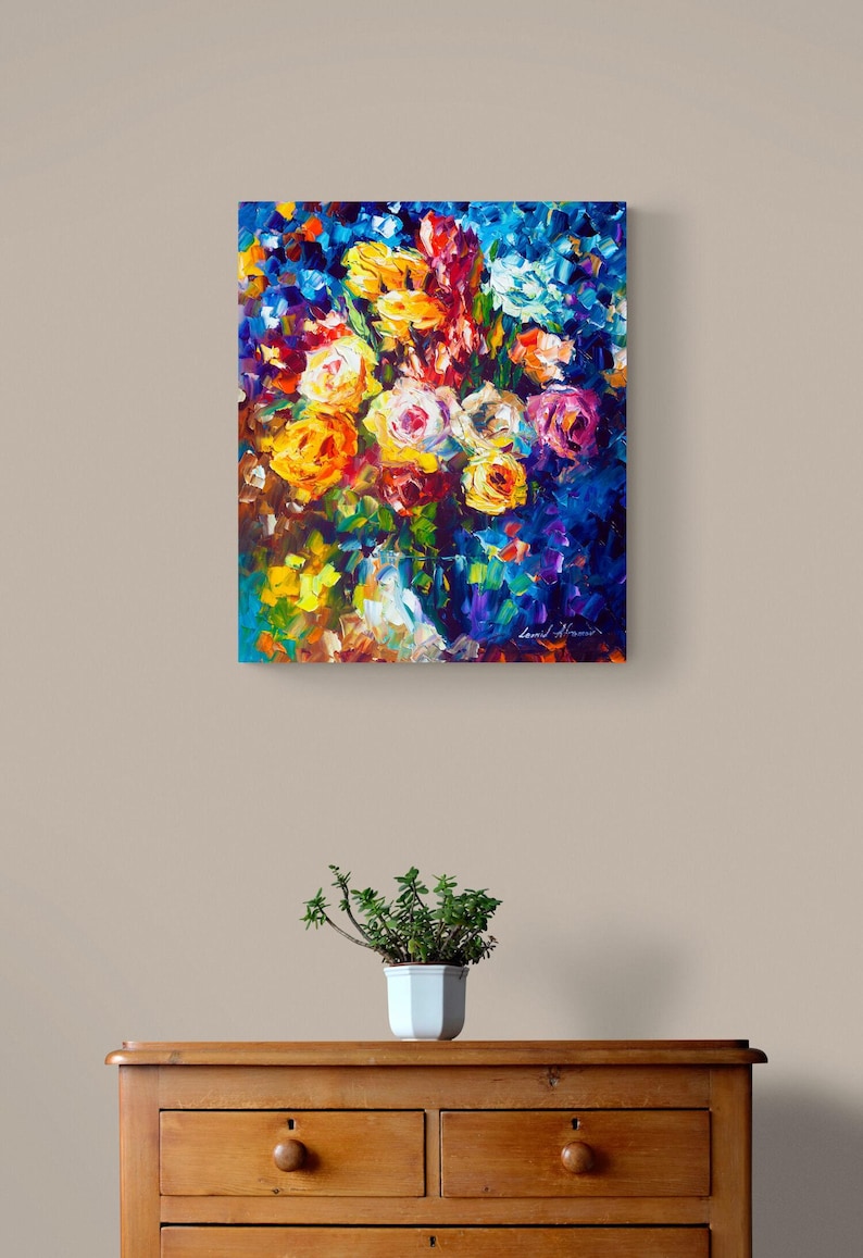 May include: An oil painting of a vibrant bouquet of flowers in shades of yellow, orange, pink, and blue. The artwork is displayed on a wall above a wooden dresser with a small potted plant.