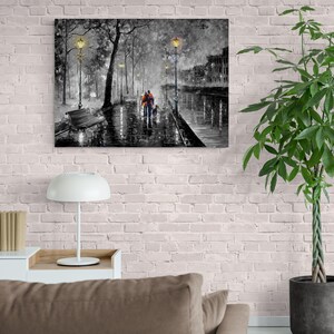 Puede incluir: Una impresi&oacute;n en lienzo en blanco y negro que representa una escena de calle lluviosa. Una pareja camina por una acera mojada con un perro, iluminada por farolas. La obra de arte presenta un banco, &aacute;rboles y edificios en el fondo.
