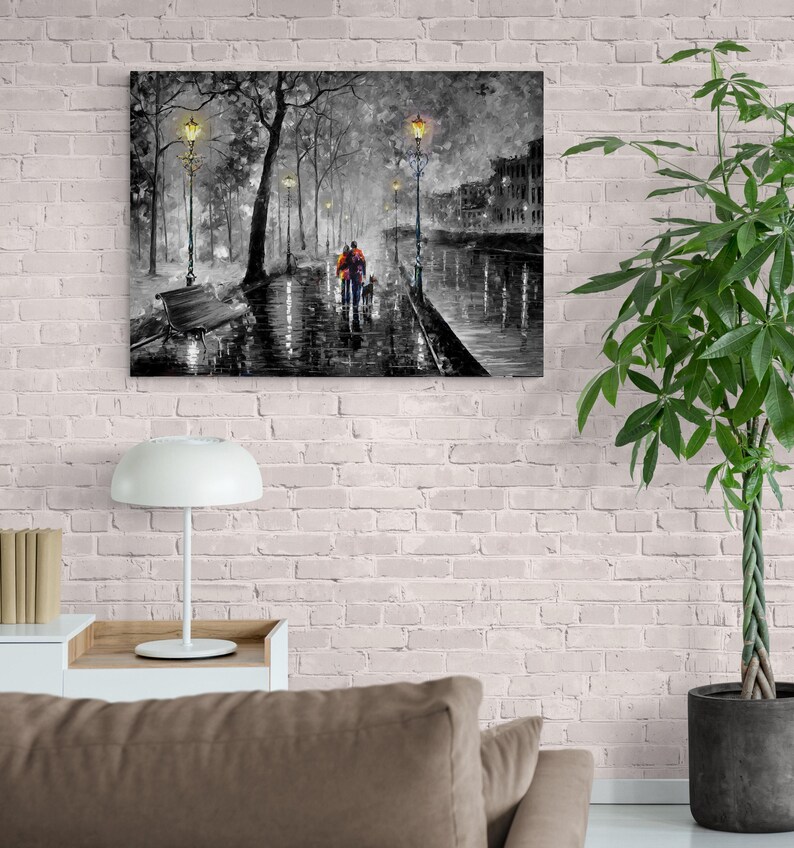 Puede incluir: Una impresi&oacute;n en lienzo en blanco y negro que representa una escena de calle lluviosa. Una pareja camina por una acera mojada con un perro, iluminada por farolas. La obra de arte presenta un banco, &aacute;rboles y edificios en el fondo.