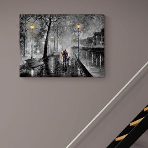 Puede incluir: Pintura al &oacute;leo en blanco y negro de una pareja paseando a un perro por un camino mojado e iluminado por l&aacute;mparas. La obra de arte representa una escena rom&aacute;ntica con un banco, &aacute;rboles y edificios al fondo. La pintura tiene una paleta de colores en escala de grises con toques de naranja.