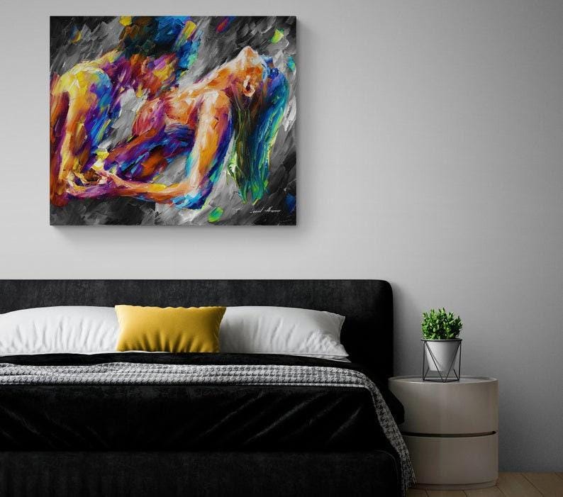 May include: Abstract painting depicting two figures in a passionate embrace. The artwork features vibrant colors including blues, yellows, and purples against a gray and black background. The painting is mounted on a wall above a bed.
