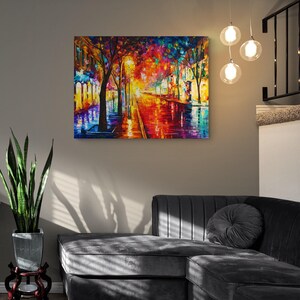 Pode incluir: Uma pintura a &oacute;leo colorida retrata uma cena de rua chuvosa com tons vibrantes de vermelho, laranja, azul e amarelo. A obra de arte est&aacute; pendurada em uma parede cinza acima de um sof&aacute; seccional cinza escuro. Tr&ecirc;s lumin&aacute;rias pendentes globais pendem do teto.