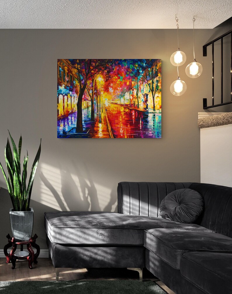 Pode incluir: Uma pintura a &oacute;leo colorida retrata uma cena de rua chuvosa com tons vibrantes de vermelho, laranja, azul e amarelo. A obra de arte est&aacute; pendurada em uma parede cinza acima de um sof&aacute; seccional cinza escuro. Tr&ecirc;s lumin&aacute;rias pendentes globais pendem do teto.
