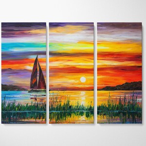 May include: A triptych canvas print depicting a sunset over water. The artwork features a sailboat with a brown sail, a bright yellow sun, and colorful sky with shades of orange, red, and blue. Green reeds are in the foreground.