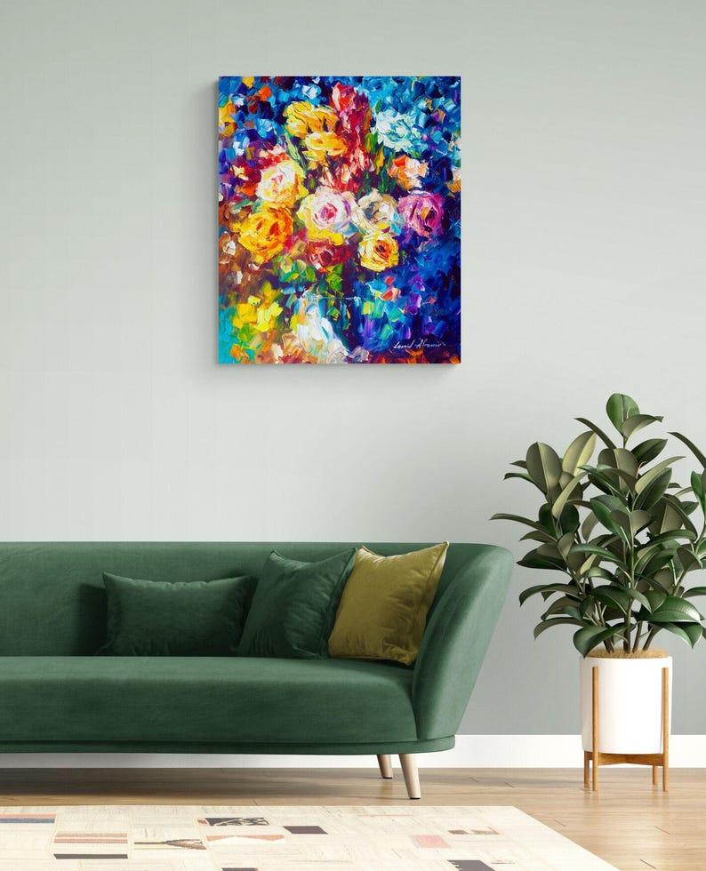 May include: An abstract floral painting with a vibrant display of colors. The artwork features a bouquet of roses in shades of yellow, orange, pink, and white against a deep blue background. The painting is displayed above a green sofa.