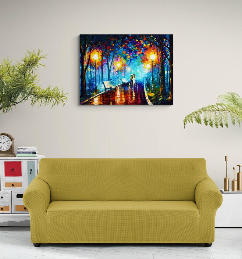May include: A colorful oil painting depicts a romantic park scene at night. The artwork features a couple walking on a wet path, illuminated by streetlights. The painting is mounted above a yellow sofa, creating a cozy atmosphere.