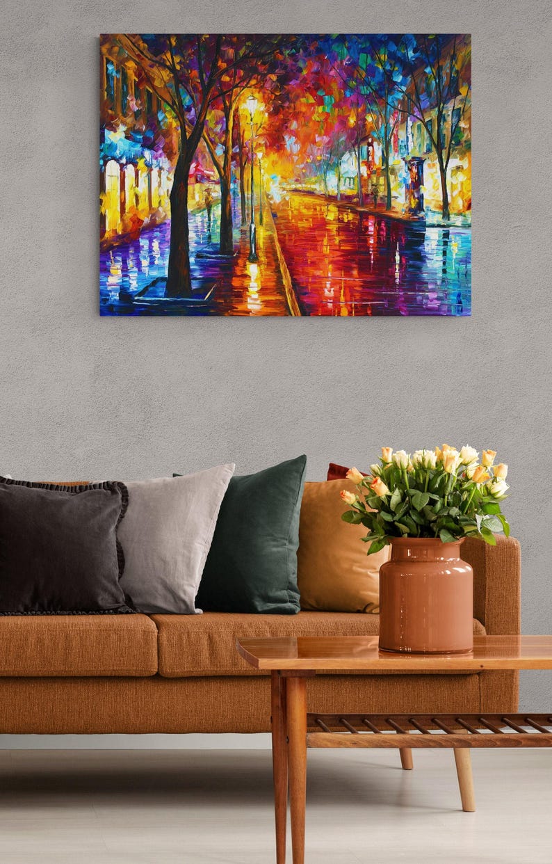 Pode incluir: Pintura a &oacute;leo de uma vibrante cena de rua noturna. A obra apresenta uma paleta colorida de vermelhos, laranjas, azuis e amarelos, com reflexos numa rua molhada. A pintura est&aacute; acima de um sof&aacute; castanho com almofadas e uma mesa de centro de madeira.