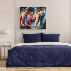 May include: Abstract painting of two figures embracing, rendered in vibrant hues of yellow, blue, orange, and purple against a dark background. The artwork hangs above a bed with a navy blue duvet and white sheets, creating a modern bedroom aesthetic.