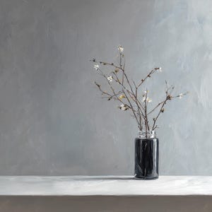 Puede incluir: Un jarrón de vidrio negro con ramas y pequeñas flores blancas. El jarrón está sobre una superficie blanca contra un fondo gris texturizado. Las ramas son delicadas y añaden un toque natural a la escena.