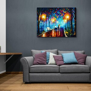 May include: A colorful oil painting depicts a romantic scene of a couple walking on a wet path in a park at night. The artwork features vibrant hues of blue, orange, and yellow, with streetlights illuminating the scene. The painting is mounted on a wall above a gray sofa.
