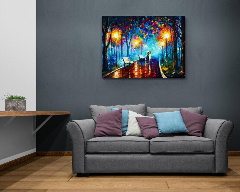 May include: A colorful oil painting depicts a romantic scene of a couple walking on a wet path in a park at night. The artwork features vibrant hues of blue, orange, and yellow, with streetlights illuminating the scene. The painting is mounted on a wall above a gray sofa.