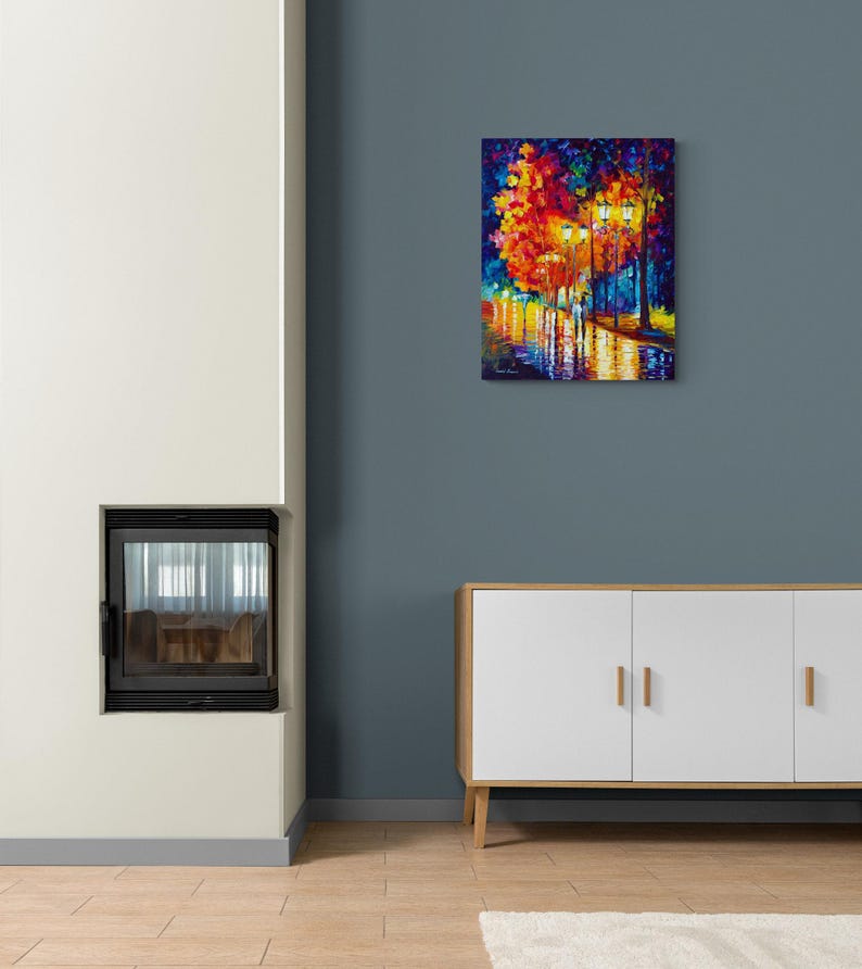 Peut inclure: Une peinture &agrave; l'huile color&eacute;e d'une sc&egrave;ne de rue nocturne. L'&oelig;uvre pr&eacute;sente des couleurs vives de rouge, orange, jaune et bleu, repr&eacute;sentant des arbres, des lampadaires et des reflets sur une surface mouill&eacute;e. La peinture est expos&eacute;e sur un mur bleu.