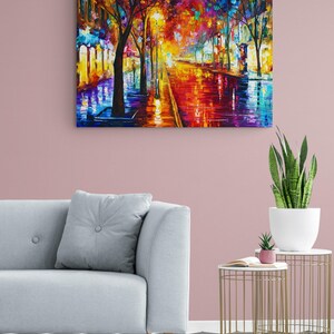 Pode incluir: Uma pintura a &oacute;leo vibrante retrata uma rua da cidade &agrave; noite, refletindo luzes coloridas em uma superf&iacute;cie molhada. A obra apresenta &aacute;rvores alinhando a rua, com uma paleta de vermelhos, laranjas, azuis e amarelos. A pintura est&aacute; pendurada em uma parede rosa.
