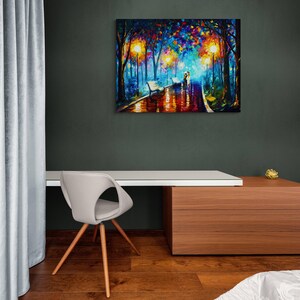 May include: A colorful oil painting depicts a romantic scene of a couple walking in a park at night. The artwork features vibrant hues of blue, orange, and yellow, with reflections on the wet pavement. The painting is displayed on a dark green wall above a white desk.