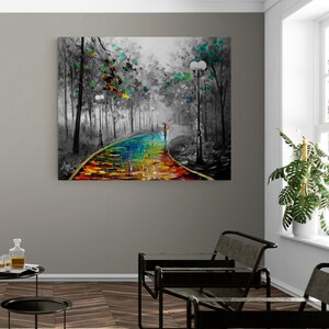 May include: A canvas art print depicts a colorful path through a black and white forest scene. The path is painted with vibrant rainbow hues, leading to a figure with an umbrella. Trees with green and yellow leaves line the path, and street lamps are visible.