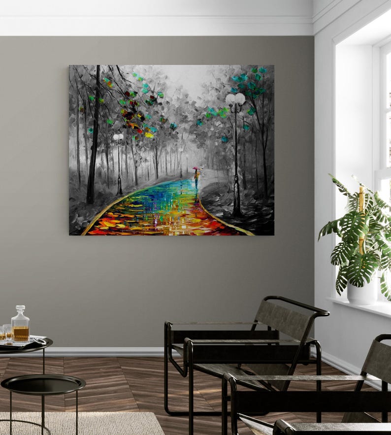 May include: A canvas art print depicts a colorful path through a black and white forest scene. The path is painted with vibrant rainbow hues, leading to a figure with an umbrella. Trees with green and yellow leaves line the path, and street lamps are visible.