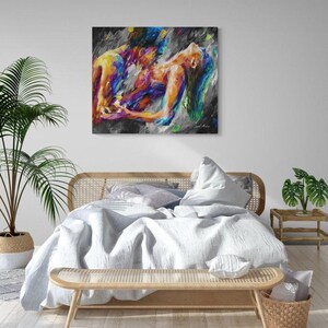 May include: Abstract art print depicting two figures in a passionate embrace. The artwork features vibrant colors, including blues, yellows, and purples, against a dark, textured background. The painting is displayed above a bed with a light blue comforter.