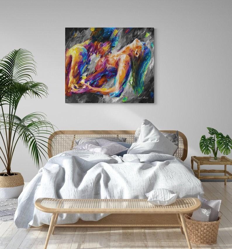 May include: Abstract art print depicting two figures in a passionate embrace. The artwork features vibrant colors, including blues, yellows, and purples, against a dark, textured background. The painting is displayed above a bed with a light blue comforter.