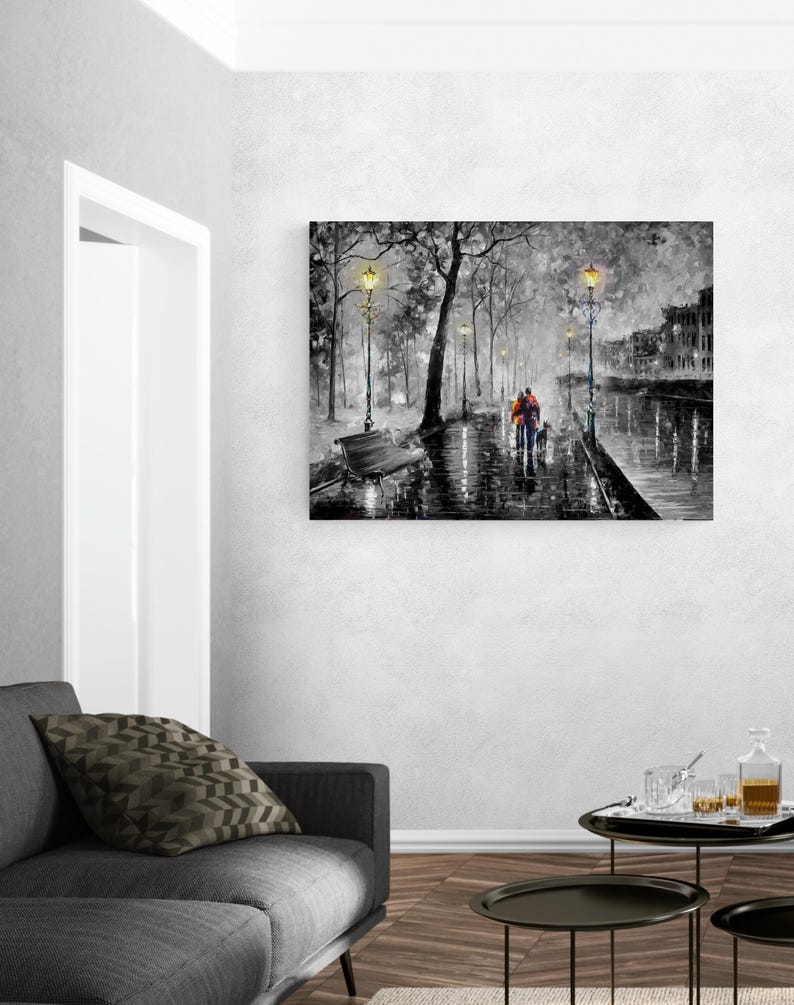 Puede incluir: Impresi&oacute;n art&iacute;stica en lienzo en blanco y negro que representa una escena de parque lluvioso con una pareja y un perro caminando por un sendero mojado. La obra presenta farolas, &aacute;rboles y edificios, con un toque de color en la ropa de las figuras.