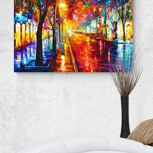 Pode incluir: Uma pintura a &oacute;leo vibrante retrata uma rua da cidade &agrave; noite, refletindo luzes coloridas em pavimento molhado. A obra apresenta uma paleta de azuis, laranjas, amarelos e roxos, com &aacute;rvores silhuetadas ao longo da rua.