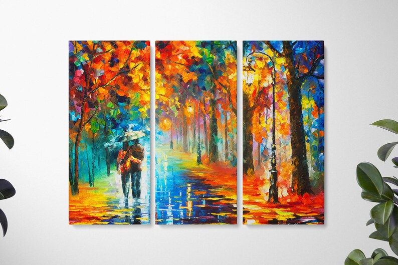 May include: A vibrant, three-panel canvas art piece depicting a couple walking under an umbrella in a colorful, impressionistic park scene. The artwork features a palette of blues, oranges, and yellows, with reflections on the wet ground and a lamppost.